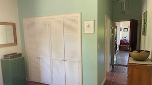Een slaapkamer met een ruime kast, een bed, een dressoir en een gang naar een andere kamer.