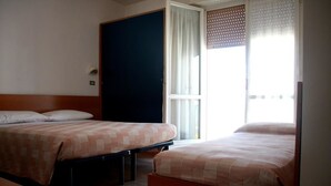 Een hotelkamer met twee bedden, een donkere kast, een raam met uitzicht en een lichtgekleurde vloer.