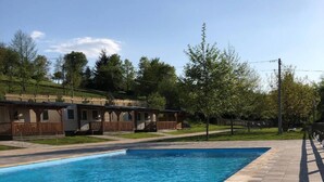 A swimming pool with a wooden deck and a covered area with benches. - Kamp Slapic Glamping (Duga Resa)