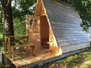 A wooden cabin with a pitched roof, a small porch, and a table.