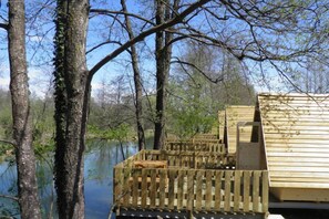 A wooden deck extending over a body of water, surrounded by trees.
