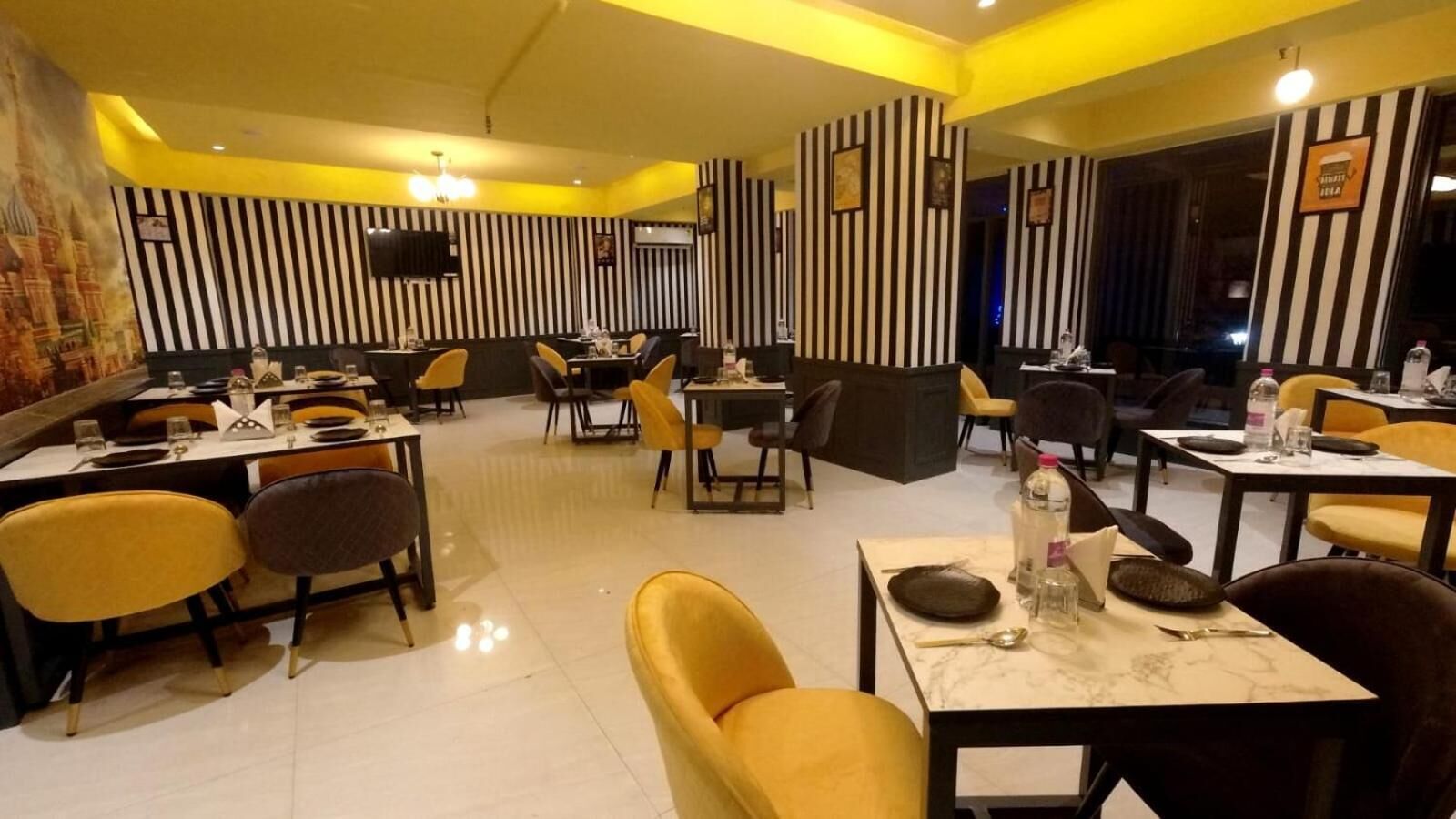 Un restaurante con paredes a rayas, sillas amarillas y mesas dispuestas para comer.