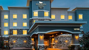 Un hôtel moderne à la façade en pierre, doté de nombreuses fenêtres et d’une enseigne bien visible indiquant « Homewood Suites Hilton ».