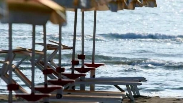 A row of beach umbrellas and lounge chairs on a sandy beach with the ocean in the background. - Hotel Sedonia (Cervia)