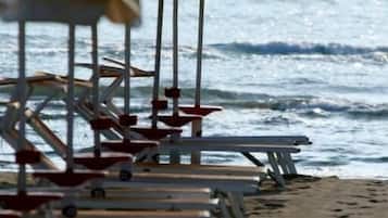 Una fila de sombrillas y sillas de playa en una arena, con el océano al fondo.