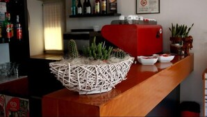 A bar area with a wicker basket containing plants, a red appliance, and various bottles on shelves. - Hotel Sedonia (Cervia)