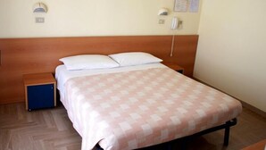 A single-bed room with a wooden headboard, a bedside table, a small blue cabinet, and a patterned bedspread. - Hotel Sedonia (Cervia)