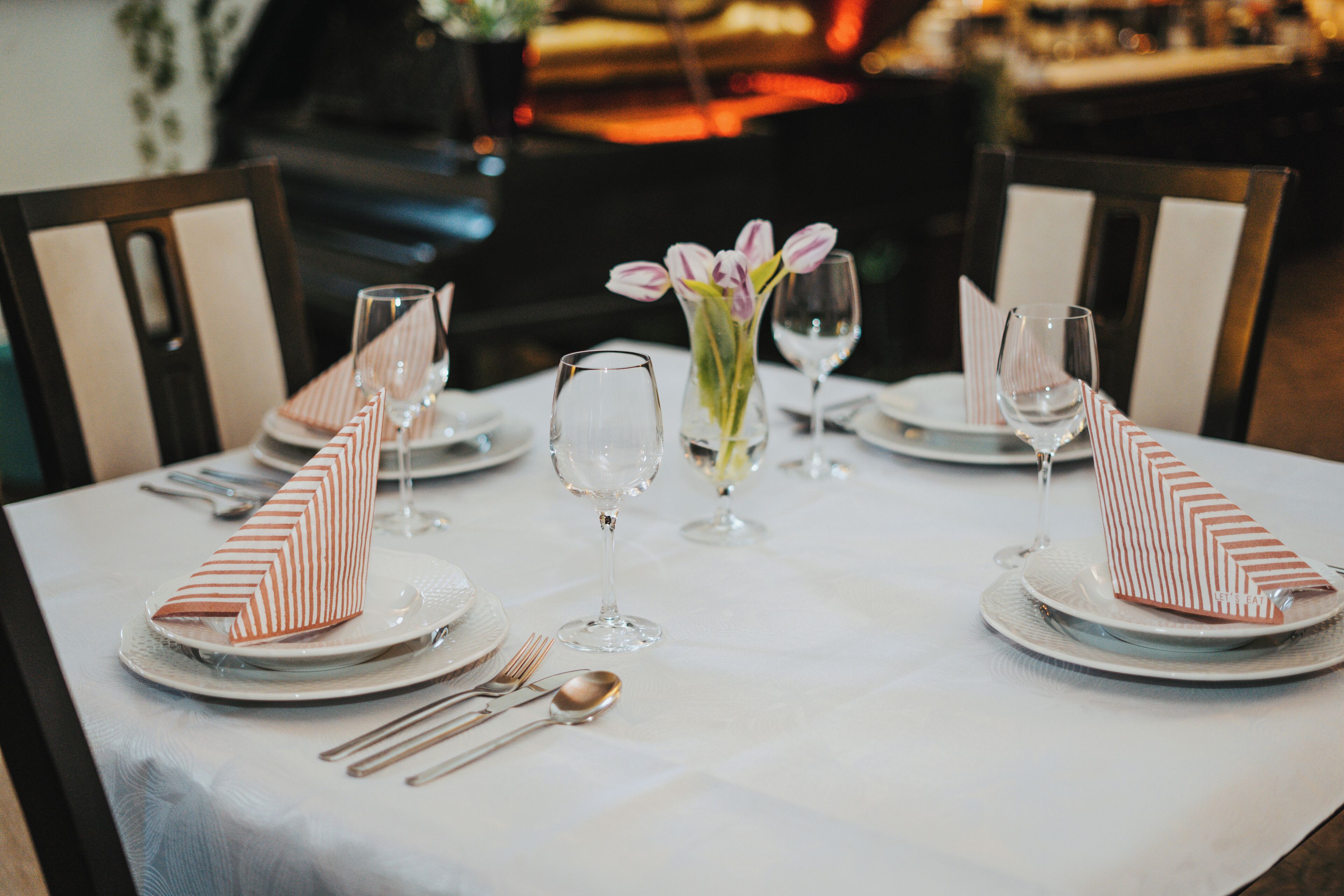 A dining table set with plates, cutlery, and napkins.