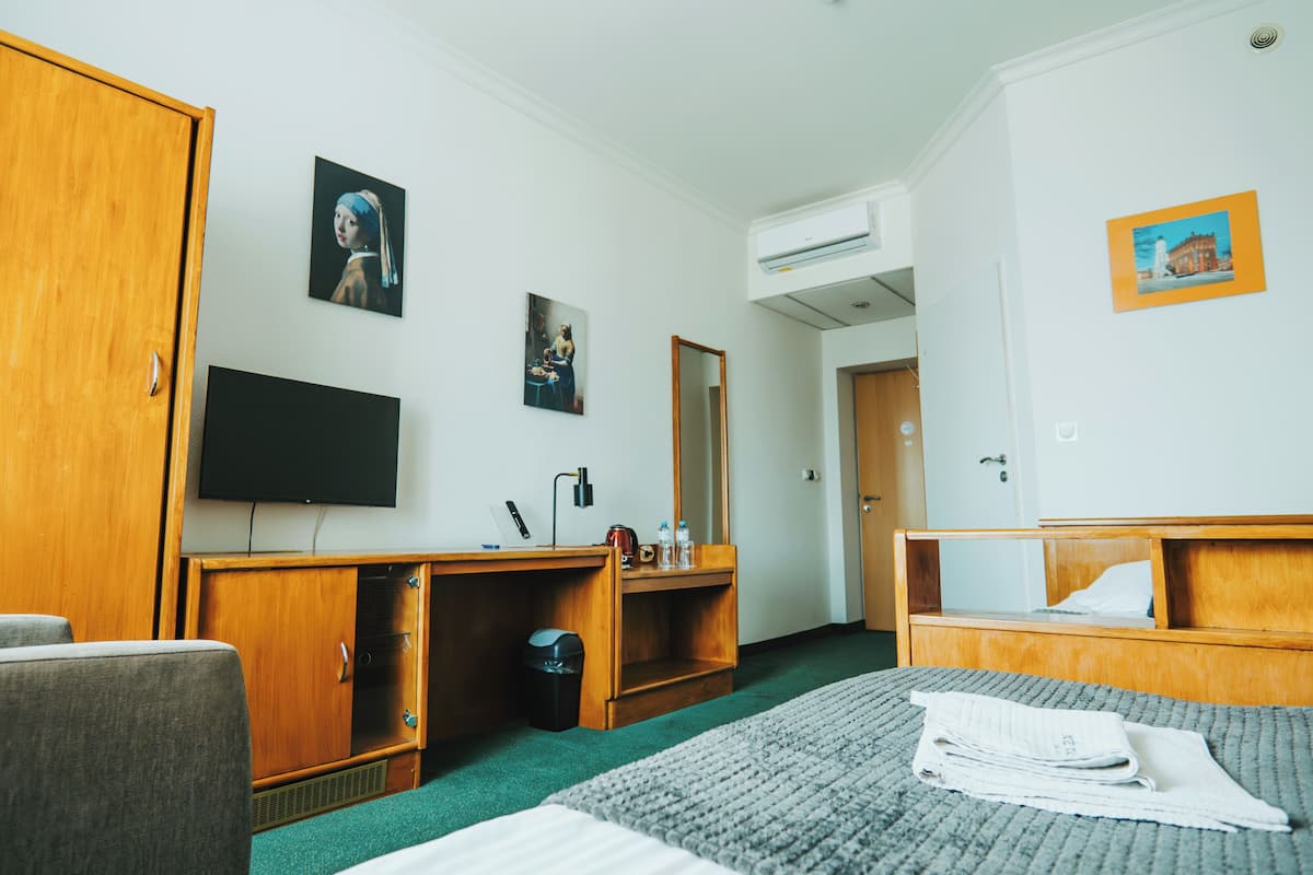 Hotellihuone, jossa on sänky, työpöytä, televisio ja vaatekaappi.