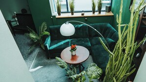 A room with a green sofa, a round table with a flower, and various plants. - Hotel Polonia Racibórz (Raciborz)
