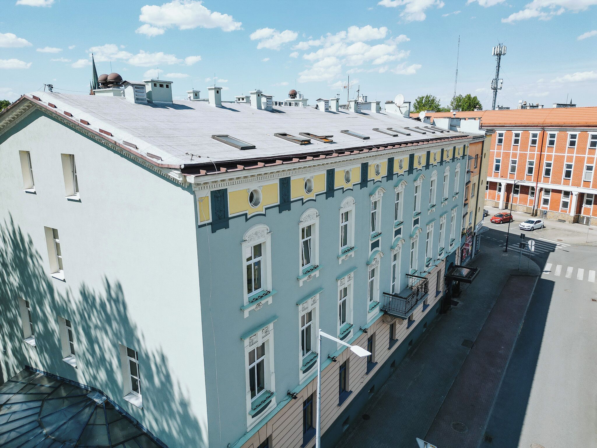 Ein mehrstöckiges Gebäude mit flachem Dach, großen Fenstern und einem Hauseingang an der Ecke.