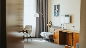 A hotel room with a bed, a desk, a chair, a lamp, and a painting on the wall. - Hotel Polonia Racibórz (Raciborz)