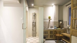 A compact hotel room with a shower, a small kitchen area, and a bed. - 101 # 1 BR Studio Apartment for solo traveler in Ubud (Ubud)