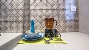 A kitchen counter with a sink, a blue towel, a glass pitcher, and a set of black utensils on a yellow placemat. - 101 # 1 BR Studio Apartment for solo traveler in Ubud (Ubud)