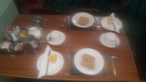A dining table set with plates, cutlery, and a teapot. - Gracelands Guest House (Blackpool)