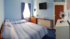 A room with two beds, a TV, a desk, and a radiator. - Gracelands Guest House (Blackpool)