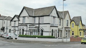 A row of white buildings with black trim, including a sign for a car park. - Gracelands Guest House (Blackpool)