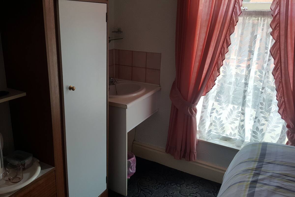 Une salle de bain avec un lavabo, des toilettes et une fenêtre avec des rideaux.