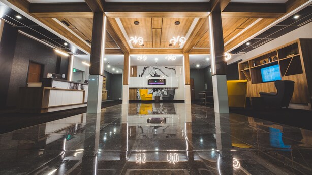 A modern lobby with a polished marble floor, wooden ceiling beams, and a reception desk with a television. - Quality Hotel & Conference Centre (Edmundston)