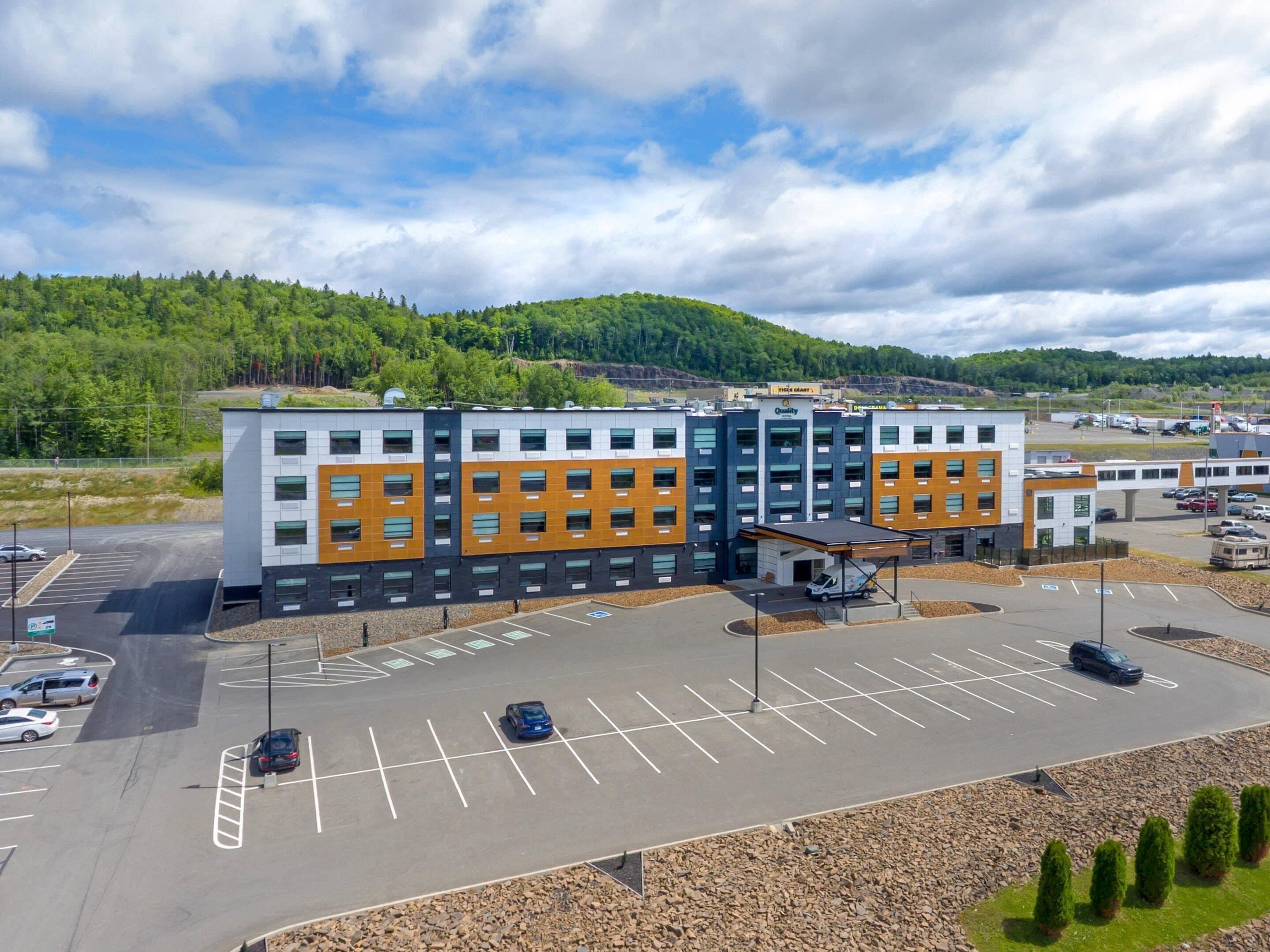 A multi-story parking structure with a covered area and a building with a sign that reads 'Quality.'