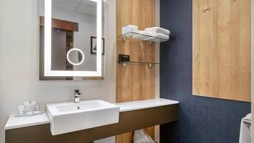 A modern bathroom with a large mirror, a white sink, and a towel rack.
