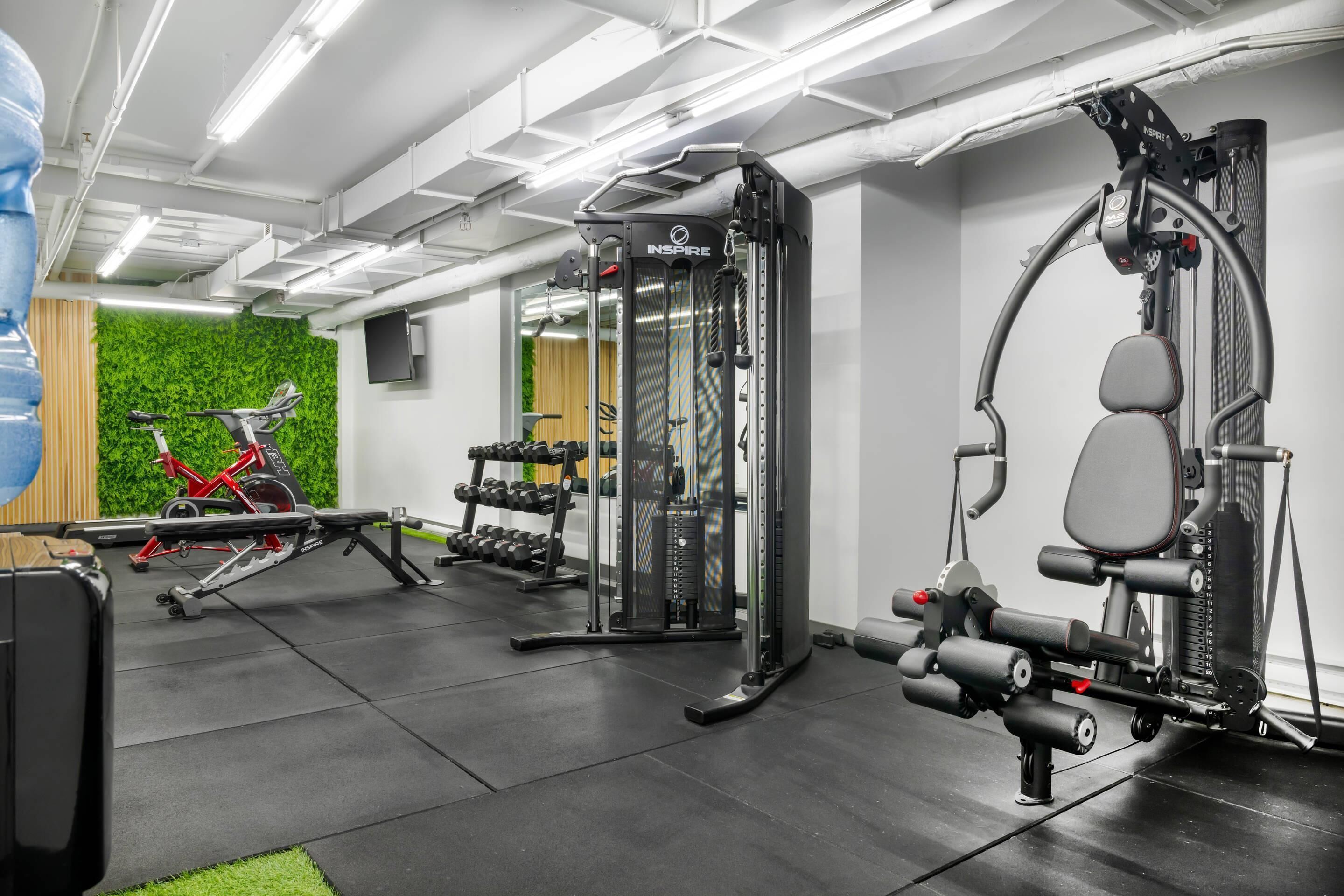 A gym with various exercise equipment, including a treadmill, weight machines, and dumbbells.