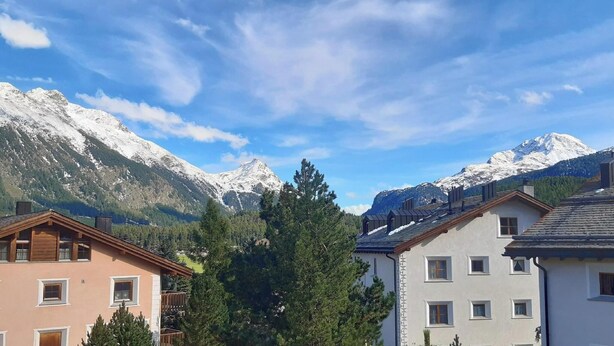 A mountain village with snow-capped peaks, wooden houses, and a clear blue sky. - The spacious 3 room apartment is located in a multi - family house at the villag (Celerina/Schlarigna)