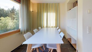 A conference room with a long white table and six white chairs, a large window with curtains, and a white shelving unit against the wall. - The spacious 3 room apartment is located in a multi - family house at the villag (Celerina/Schlarigna)