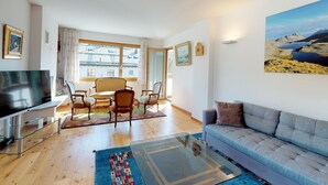 A modern living room with a sofa, a TV, and a dining area with chairs and a table. - The spacious 3 room apartment is located in a multi - family house at the villag (Celerina/Schlarigna)
