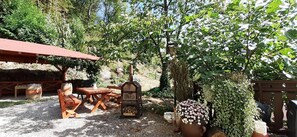 An outdoor patio with wooden furniture, a barbecue grill, and a flower pot. - Gästehaus Gerhardt (Schweigen-Rechtenbach)