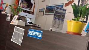 Un mostrador de recepción con un cartel de 'No fumar', un letrero de 'Recepción' y un mapa enmarcado en la pared.