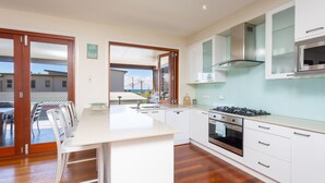 Cocina moderna con isla central, muebles blancos, extractor de acero inoxidable y vistas al exterior.