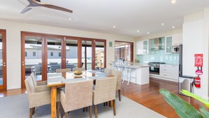 Una cocina moderna con una isla central, un comedor con mesa y sillas, y vistas al exterior.