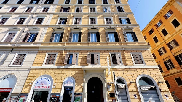 Un edificio de varios pisos con un estilo arquitectónico clásico, que presenta ventanas en arco y una entrada central.