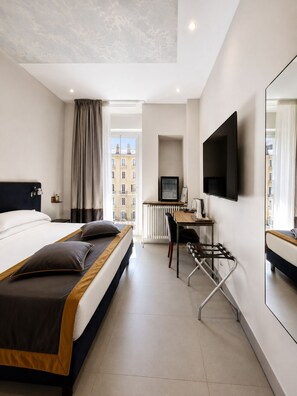 A hotel room with a bed, a desk, a chair, a TV, and a window with curtains. - Opera 58 (Rome)