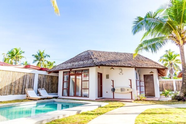 A house with a pool, a thatched roof, and a surfboard leaning against the wall. - Blauset House Ii (General Luna)