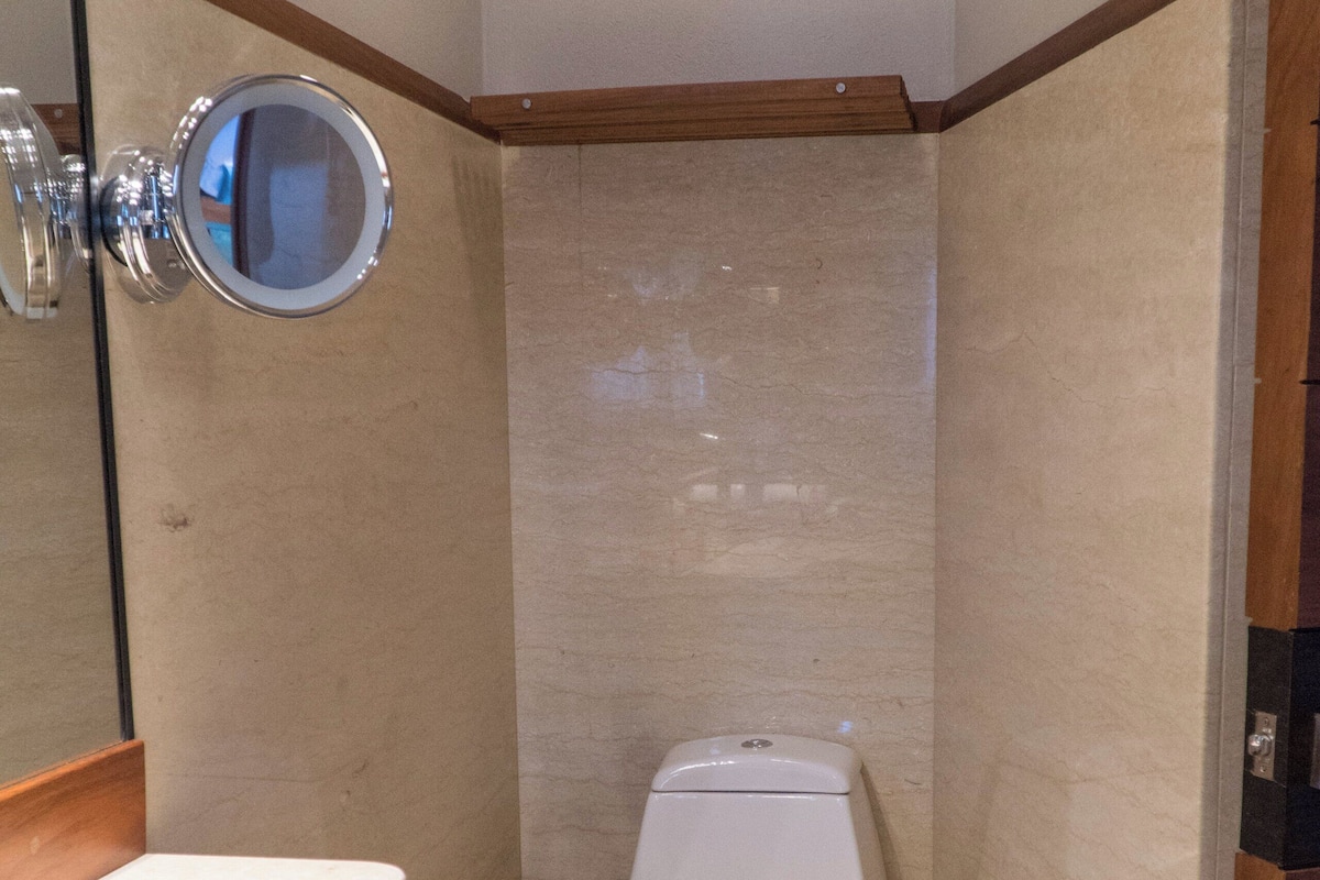 A compact bathroom with a toilet, a mirror, and a towel rack.