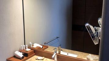 Une salle de bain moderne avec un grand miroir, un lavabo et un espace coiffeuse.