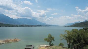 A lake with mountains in the background, a dock, and trees.