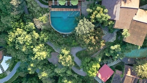 An aerial view of a resort with a central swimming pool, surrounded by lush greenery and multiple buildings with tiled roofs. - Gamma Monterrey Rincón de Santiago. (Santiago)