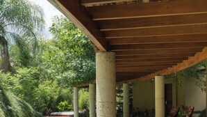A covered walkway with a pool, surrounded by greenery and columns. - Gamma Monterrey Rincón de Santiago. (Santiago)