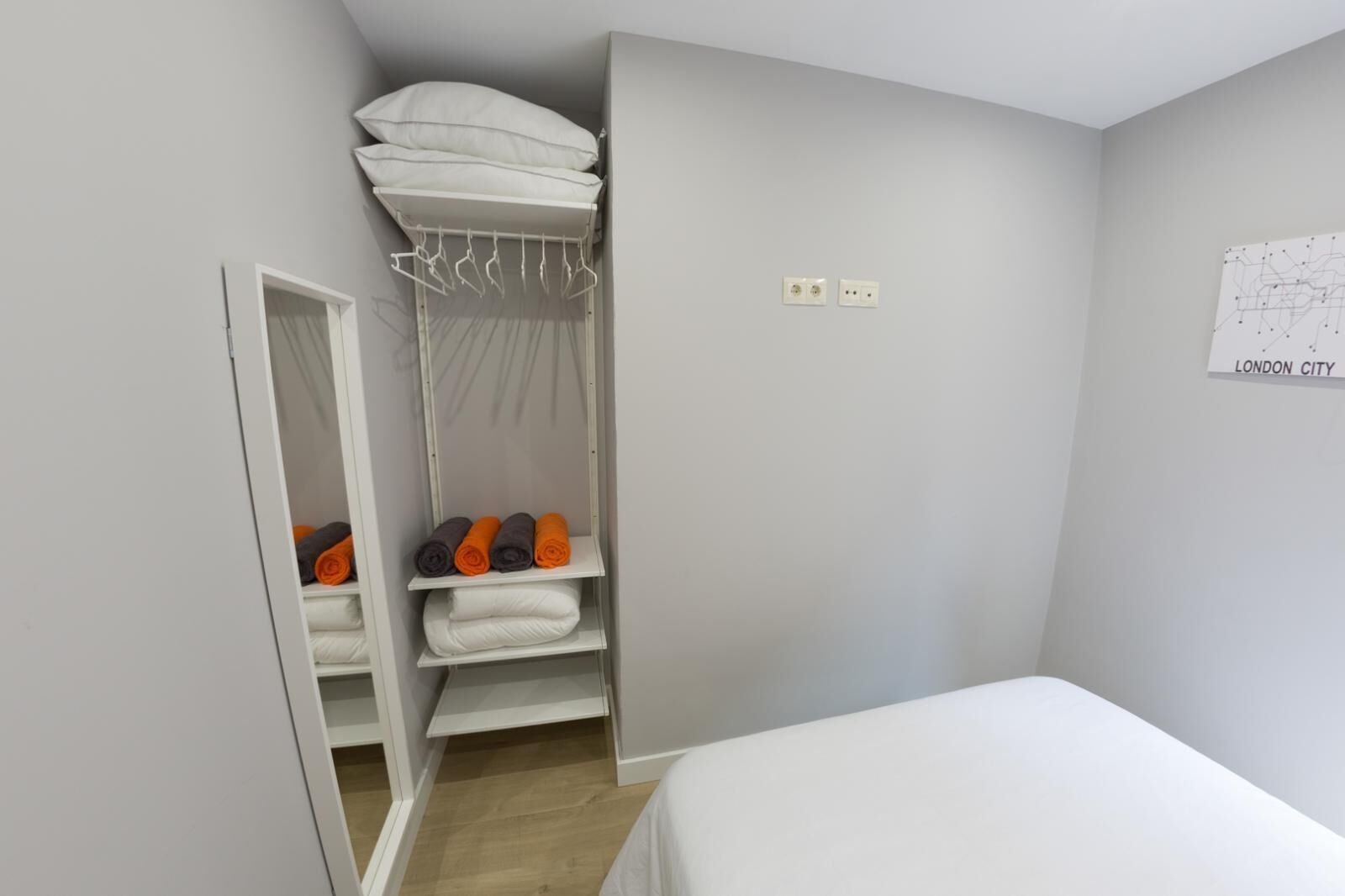 Un dormitorio con cama, armario con espacio para colgar y espejo.