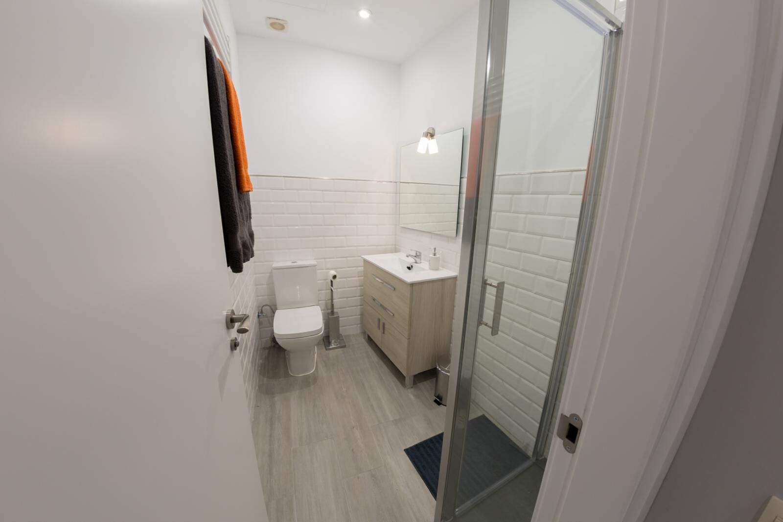 Ein modernes Badezimmer mit Toilette, Waschbecken und einer Duschkabine aus Glas.
