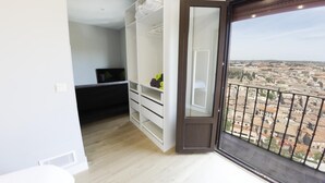 A balcony with a city view, a wardrobe with shelves, and a television on a stand.
