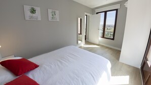 Un dormitorio con una cama grande, dos almohadas rojas y dos obras de arte colgadas en la pared.