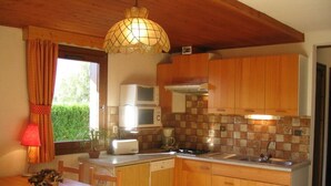 Una cucina compatta con mobili in legno, un forno a microonde, un tostapane e un lavello.