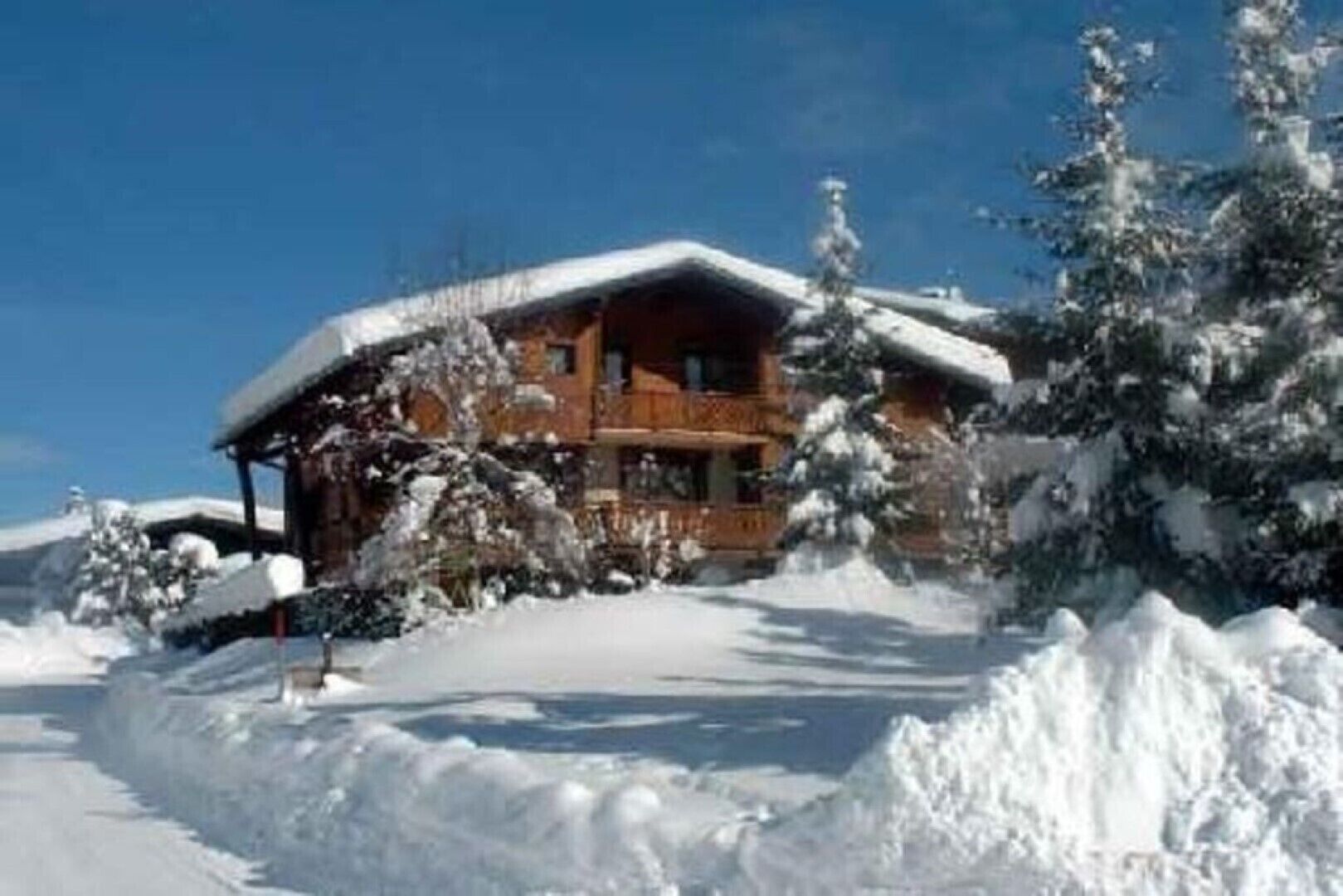 Eine Holzhütte mit schneebedecktem Dach, umgeben von Schnee.