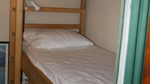 A bunk bed with white bedding and a lamp on the top bunk. - Studio Le Colombier N ° 18 (Aillon-le-Jeune)
