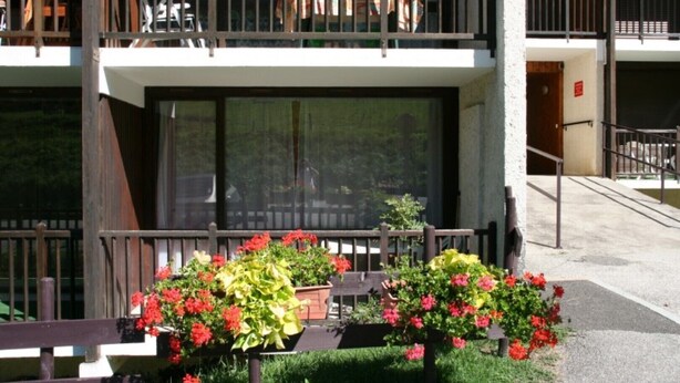 A modern building with a balcony, a staircase, and flower planters. - Studio Le Colombier N ° 18 (Aillon-le-Jeune)