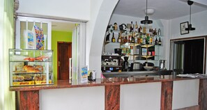 A hotel lobby with a marble reception desk, a glass display case with pastries, and a wall-mounted liquor shelf. - Hotel Maruxa (Sanxenxo)